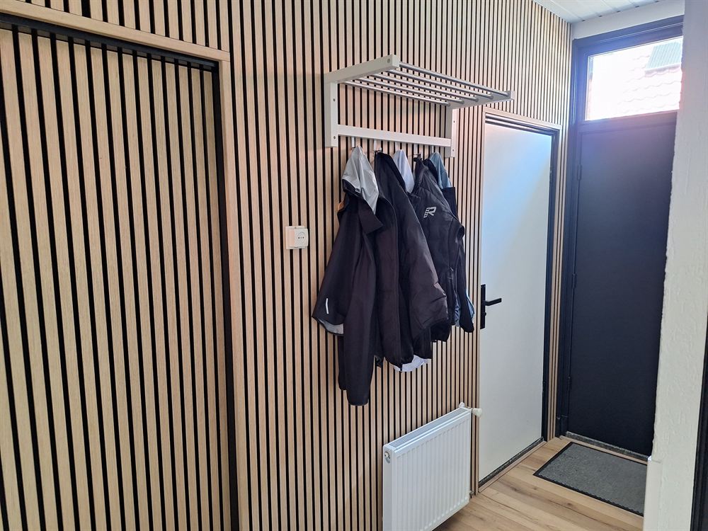 De hal met een wand van houten latten, kapstok en de voordeur